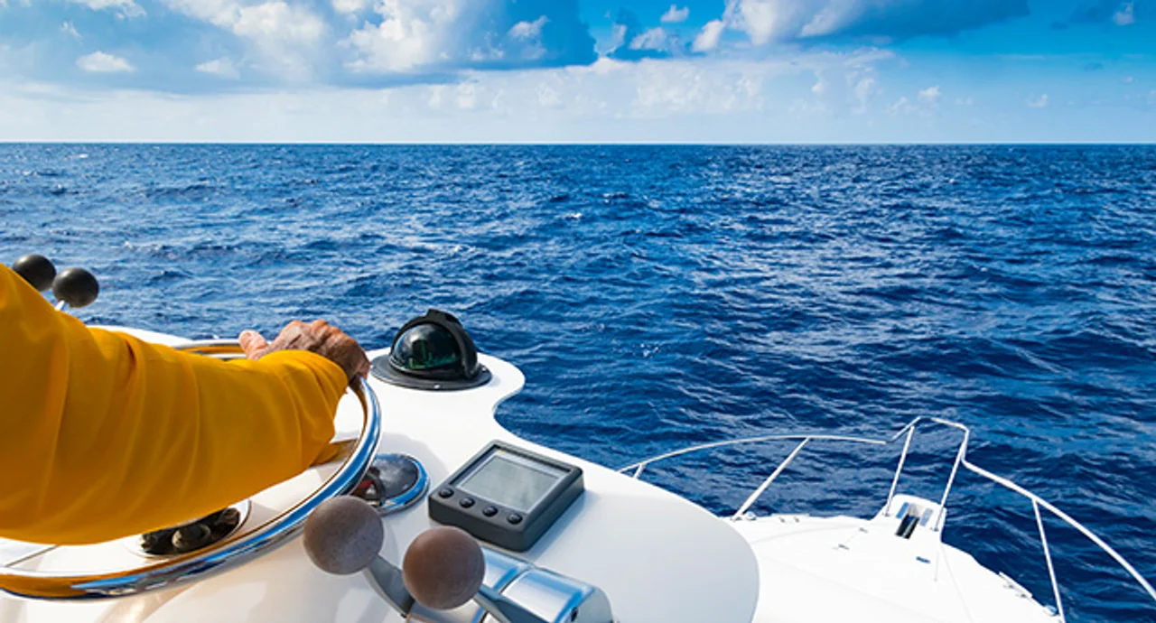 The hand of the captain at the wheel of a motorboat in the blue ocean